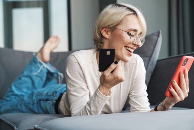 Frau mit Kreecitkarte in der Hand und in der anderen ein Smartphone